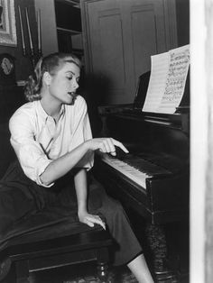 a woman sitting at a piano with sheet music behind her