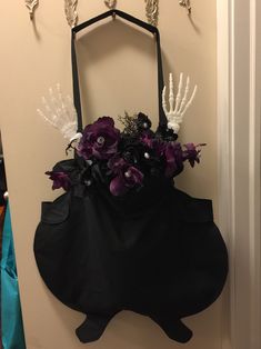 a black purse with purple flowers and skeleton hands hanging on the wall