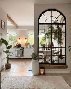 a living room filled with furniture and a large window next to a white rug on top of a hard wood floor