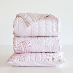 three pink quilted bedspreads stacked on top of each other in front of a white wall