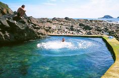 a man sitting on the edge of a rock pool