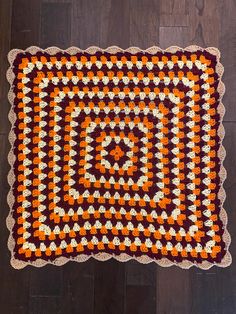 an orange and white crocheted afghan on a wooden floor