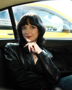 a woman sitting in the back seat of a car with her hand on her chin