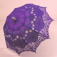 an open purple lace umbrella on a pink background