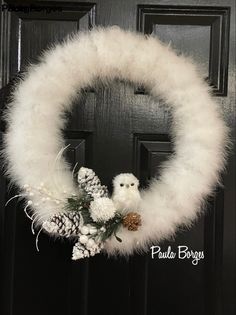 a white wreath with pine cones and an owl on it is hanging from the front door