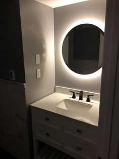 a bathroom with a sink, mirror and light on the wall above it's counter