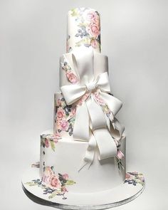 a three tiered cake decorated with flowers and ribbons