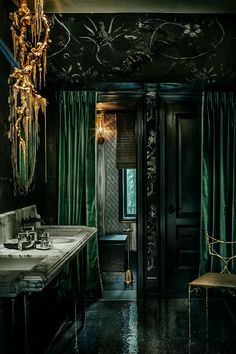 a bathroom with black walls, green curtains and a chandelier hanging from the ceiling