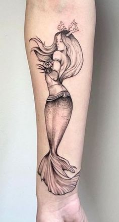 a woman's leg with a mermaid tattoo on it