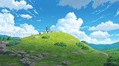 two people standing on top of a lush green hill under a blue sky with clouds