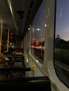 people are sitting on the bus at night with their backs turned to the side as they look out the window