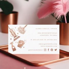 a business card sitting on top of a tray next to a pink flower and potted plant