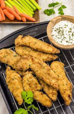 chicken tenders on a grill with carrots and celery next to dip