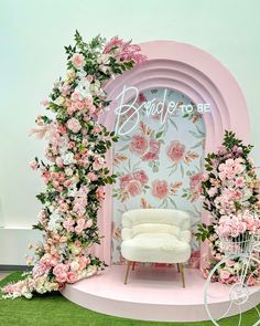 a white chair sitting on top of a lush green field next to a flower covered wall