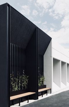 two benches with plants growing out of them in front of a white building on a cloudy day