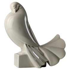 a white bird figurine sitting on top of a stand with its beak open