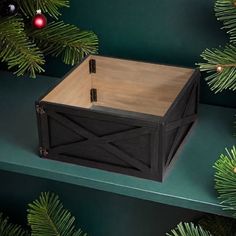 a wooden box sitting on top of a green shelf next to christmas tree branches and ornaments