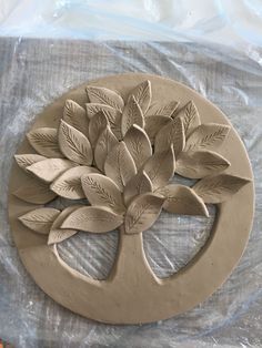 a clay sculpture of a tree with leaves in the center on a sheet of plastic