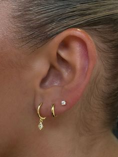 a close up of a person's ear with two small diamond earrings on it