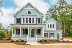 a blue house with white trim on the front porch and two story, three car garage