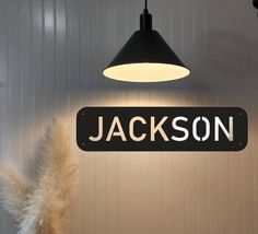 a black and white sign hanging from the side of a wall next to a plant