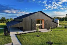 an aerial view of a barn with a large yard and trees in the foreground