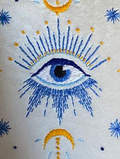 an eye with the sun and moon on it is painted in blue, yellow and white