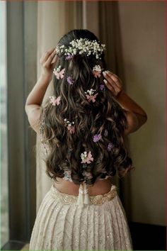 the back of a woman's head with flowers in her hair and dress on