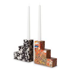 three candles sitting on top of each other in front of a white background with black and orange designs