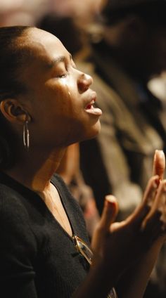 a woman sitting in front of an audience with her hands together