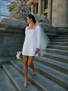 a woman in a white dress is standing on some steps