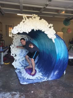 a man riding a wave on top of a surfboard in a room filled with furniture