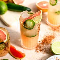 two glasses filled with different types of drinks and garnished with limes, pepperoni, cucumbers, and watermelon