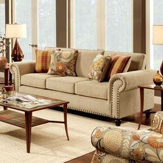 a living room filled with lots of furniture next to large windows and floor lamps on either side of the couch