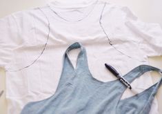 a pair of scissors laying on top of a white t - shirt next to an apron