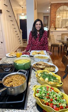 a woman standing in front of a table filled with different types of food on plates