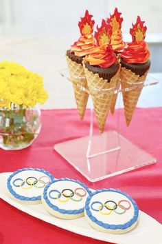 the olympic desserts are on display in front of yellow flowers and cupcakes