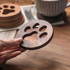 a person holding a wooden cut out of a dog's paw on top of a table