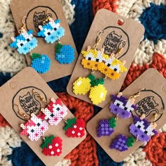 four pairs of earrings made out of perler beads are on a knitted surface