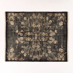 an old rug with flowers and leaves on the bottom is shown in black, beige, and white colors