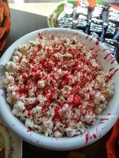 a white bowl filled with popcorn covered in red and white sprinkles on top of a table