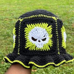 a person wearing a crocheted hat with a skull on the front and green grass in the background