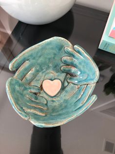 a ceramic bowl with two hands holding a heart