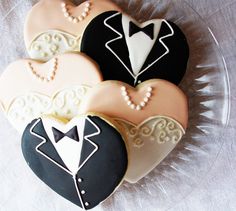 three decorated cookies in the shape of groom and bride's suits on a clear plate