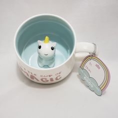 a little cup of water with a small toy unicorn in the bowl next to it