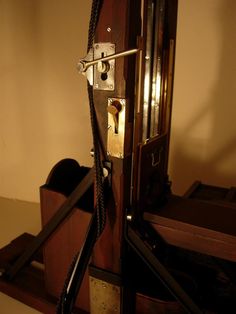 an old fashioned clock with two dials on it's face and rope hanging from the front