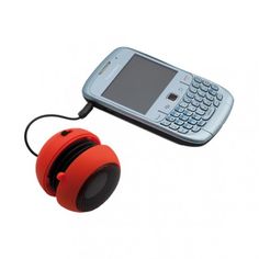 a cell phone is plugged into an orange speaker with a cord attached to it