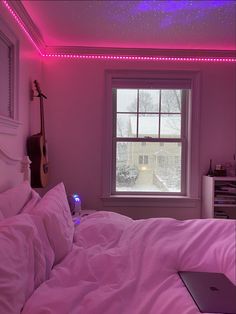 a laptop computer sitting on top of a bed in a room with pink walls and ceiling lights