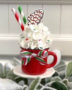 a red cup filled with whipped cream and candy canes on top of a plate