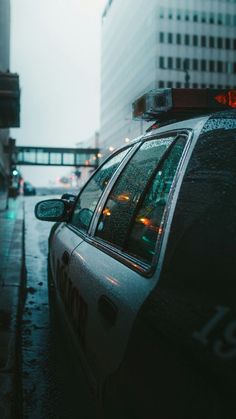 a police car is parked on the side of the road in front of tall buildings